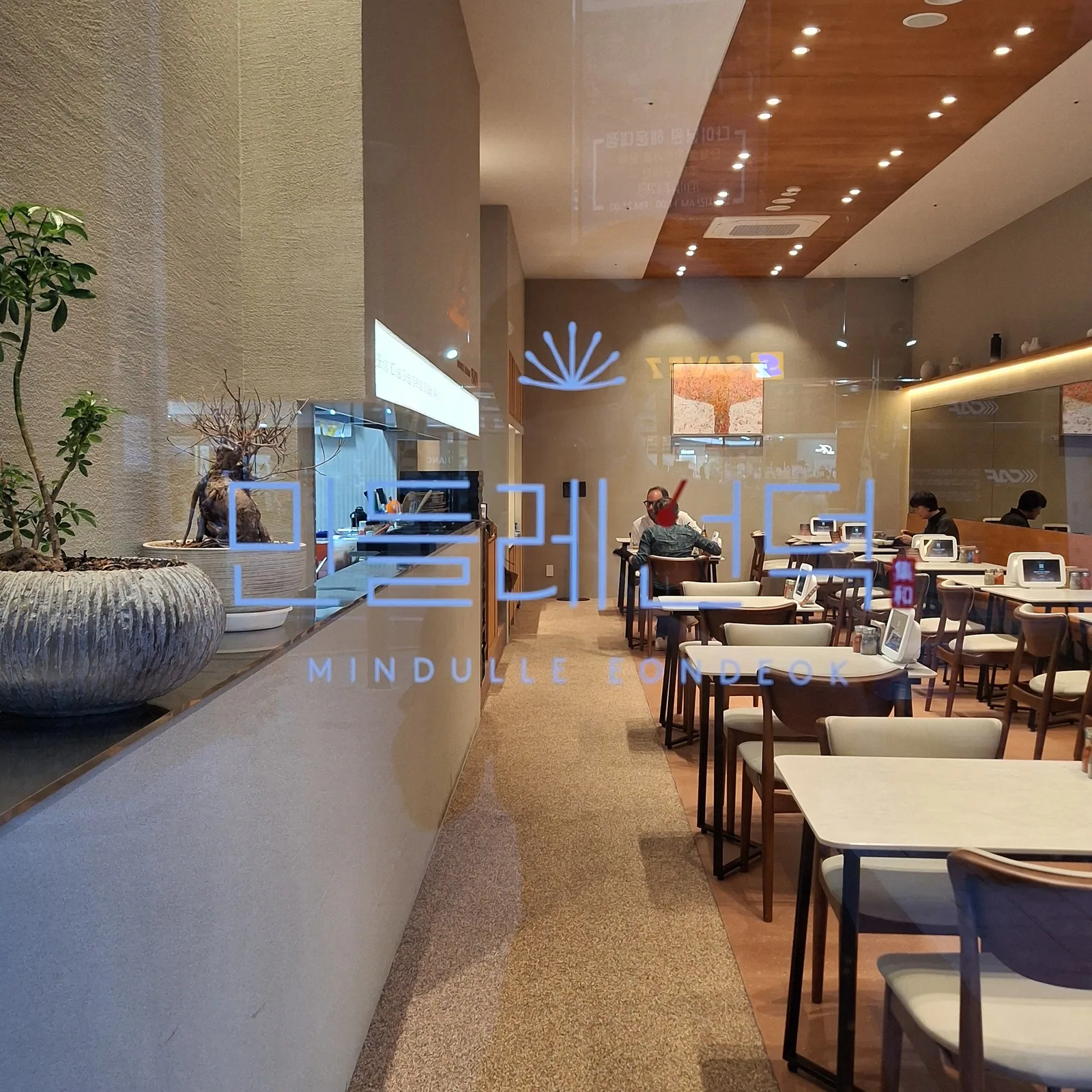 The Mindulle Eondeok lettering on the entrance glass, with the dining room beyond