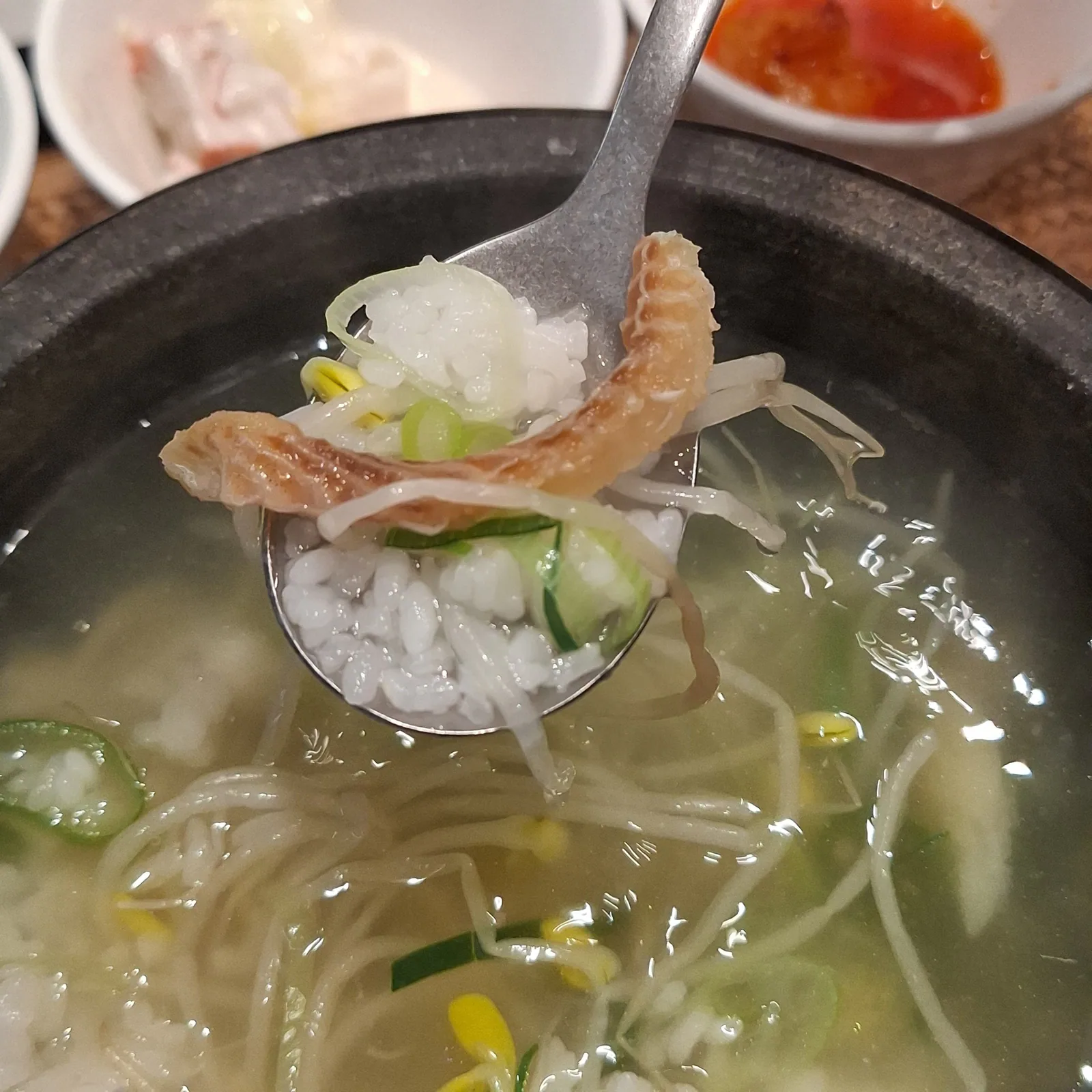 A spoonful of the soup with pollack, bean sprouts and rice