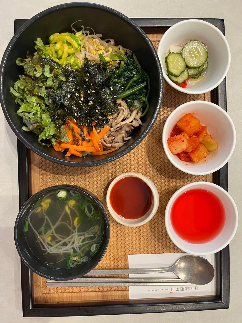 Vegan bibimbap with vegetables, seasoned greens, mushrooms and seaweed, served with soup and side dishes